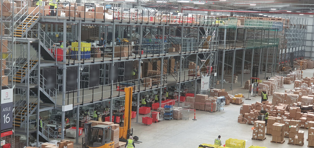 Overhead view of a worker pulling a pallet truck through warehouse pallet racking aisles after a SEMA rack inspection.